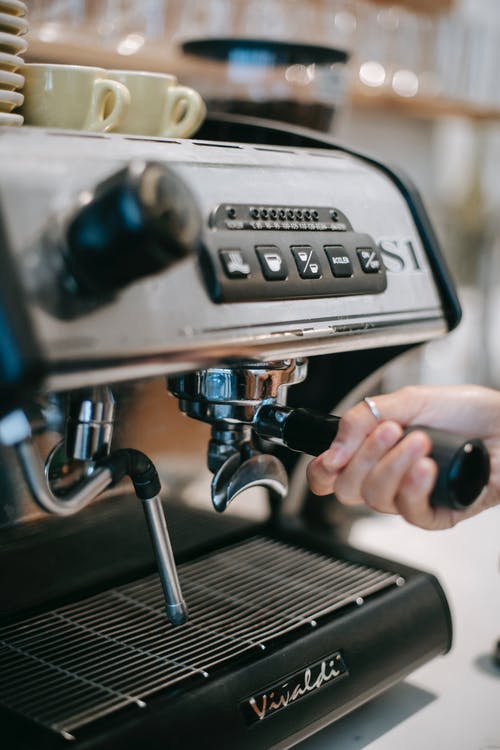 作物咖啡师将portafilter插入咖啡机 · 免费素材图片