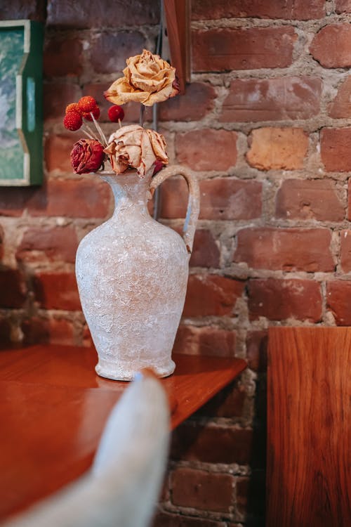 花瓶与干玫瑰木制的桌子上 · 免费素材图片