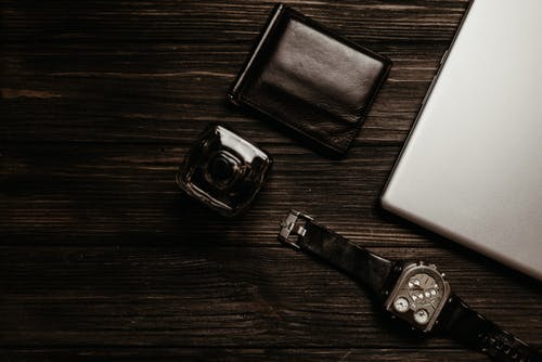 银色数字手表旁边的黑色皮革双折钱包 · 免费素材图片