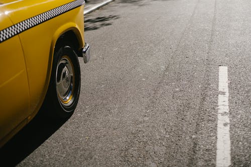 在柏油马路上行驶的黄色出租车 · 免费素材图片