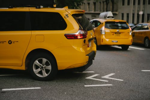 沿着城市街道骑的黄色出租车 · 免费素材图片