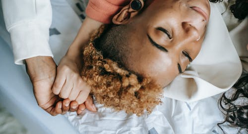 裁剪黑人妇女在床上休息，握着女朋友的手 · 免费素材图片