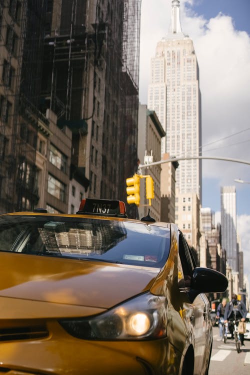 现代出租车与闪亮的大灯，在城市道路上 · 免费素材图片