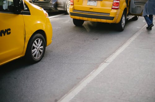 变得面目全非的人在城市街道上捉黄色出租车 · 免费素材图片