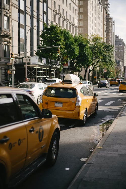 现代黄色出租车在市中心的沥青路面上骑 · 免费素材图片
