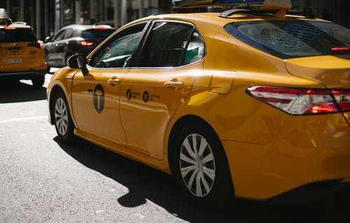 闪亮的黄色出租车，沿着市区繁忙的街道 · 免费素材图片