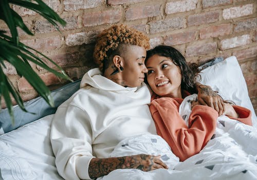 在家拥抱在床上的微笑的同性恋不同的妇女 · 免费素材图片