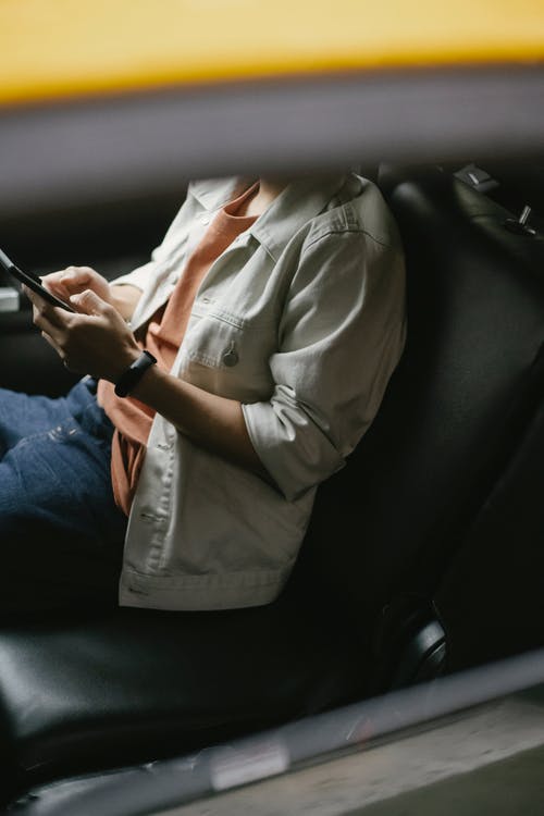 裁剪男子坐在出租车和浏览智能手机 · 免费素材图片
