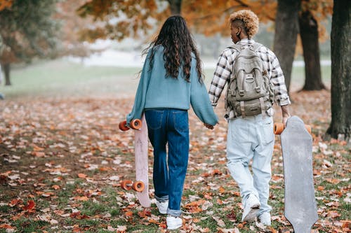 不同的女同性恋夫妇在高大的树木之间背着长板 · 免费素材图片