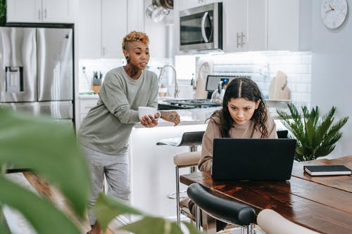 不同的妇女在有膝上型计算机的厨房里 · 免费素材图片
