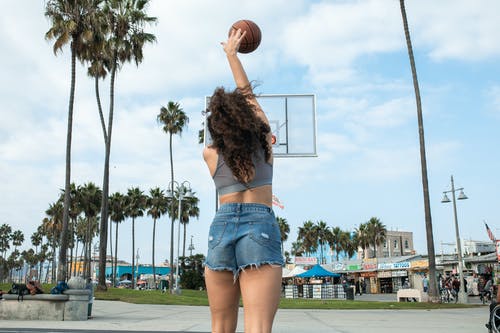拿着篮球的蓝色牛仔短裤的女人 · 免费素材图片