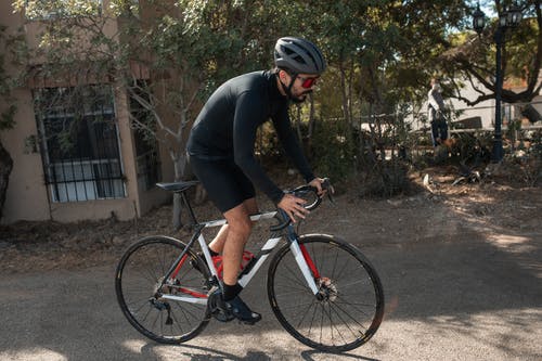 黑色长袖衬衫骑红色和白色公路自行车的人 · 免费素材图片
