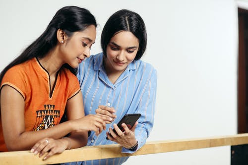 不同的女朋友在木栅栏附近的智能手机上上网 · 免费素材图片