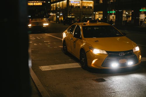晚上在现代城市的道路上行驶的出租车车和公共汽车 · 免费素材图片