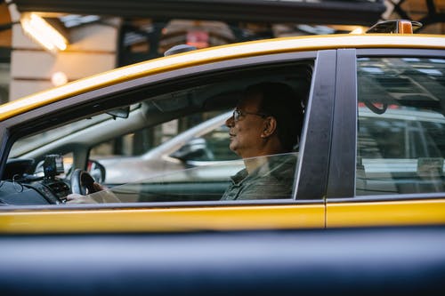 亚洲男子驾驶黄色出租车 · 免费素材图片