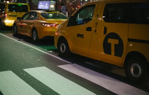 黄色出租车在市区晚上停在沥青路边 · 免费素材图片