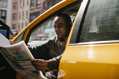种族的人坐在出租车与报纸 · 免费素材图片