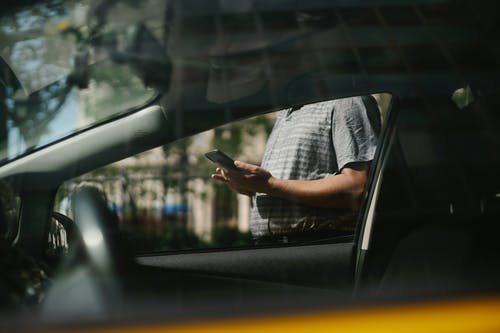 在出租车附近使用智能手机的人 · 免费素材图片