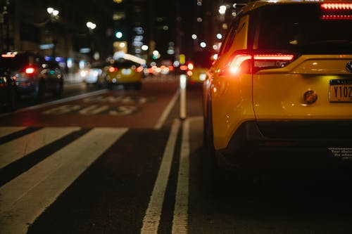 晚上在城市街道上行驶的时尚黄色suv汽车 · 免费素材图片