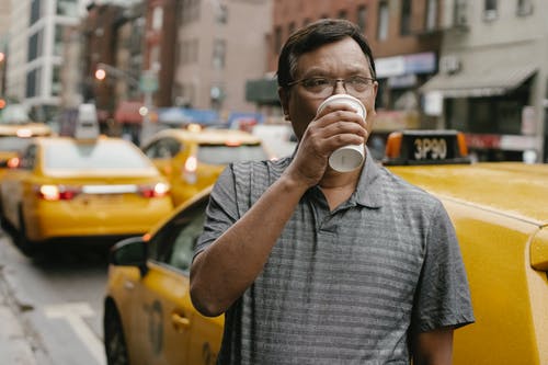 体贴的亚裔男子，驾驶室附近喝咖啡 · 免费素材图片