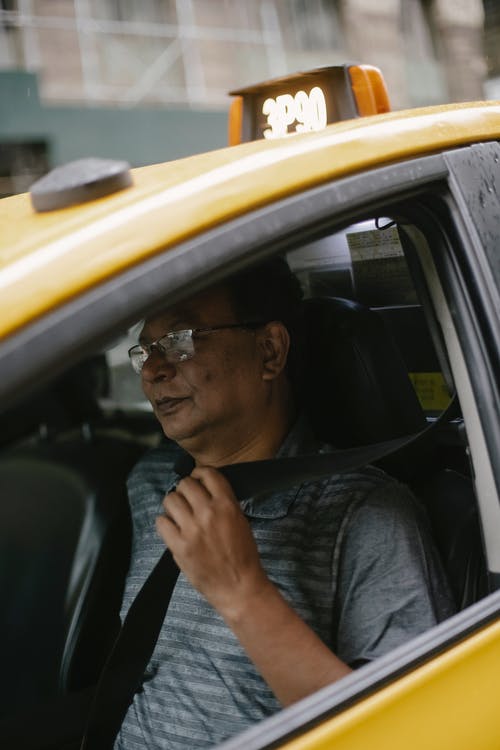 自信的民族男人，在黄色出租车上系好安全带 · 免费素材图片