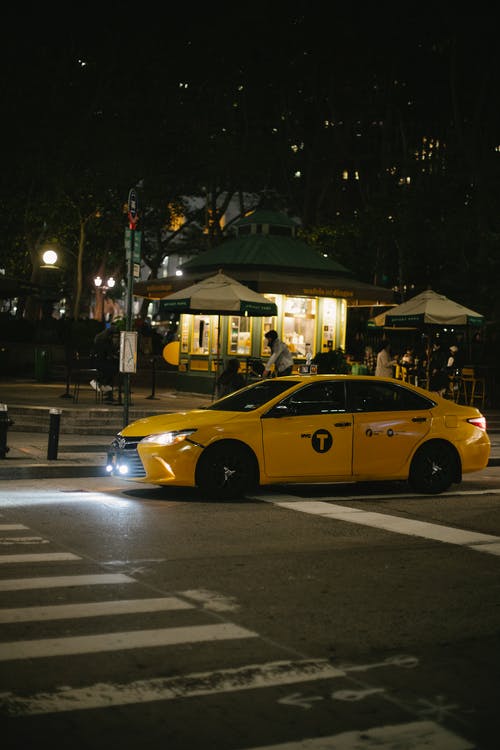 在夜间斑马线附近城市街道上的当代出租车 · 免费素材图片