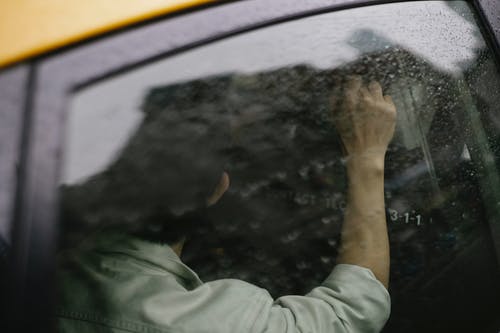 不可识别的人在雨天坐在黄色出租车的后座上 · 免费素材图片