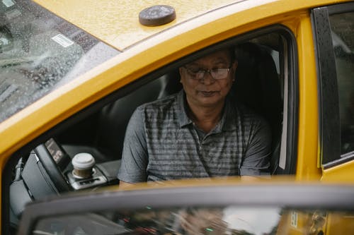 坐在打开的出租车车里的严肃的民族人 · 免费素材图片