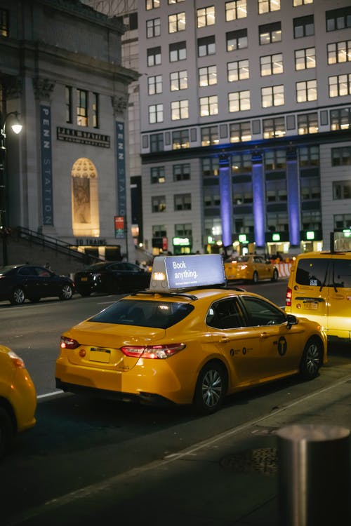 晚上在多级建筑物附近的城市街道上乘坐时尚的出租车 · 免费素材图片