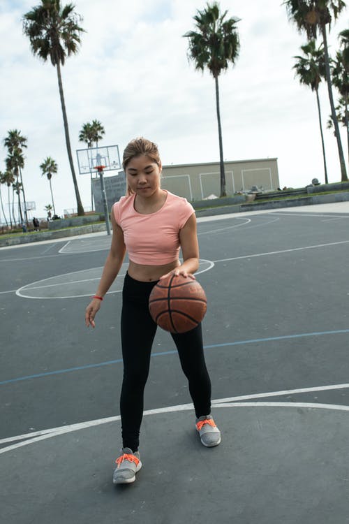 粉红色的背心和黑色的裤子，拿着篮球的女人 · 免费素材图片