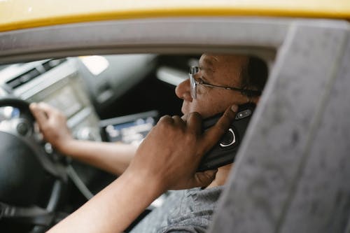 族裔人在车里的智能手机上聊天 · 免费素材图片