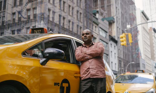 自信的民族出租车司机靠在城市的汽车 · 免费素材图片