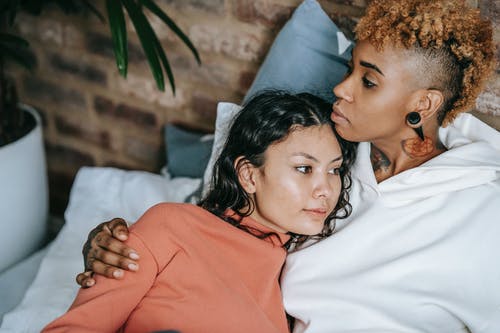 作物多种族女同性恋夫妇拥抱在床上 · 免费素材图片
