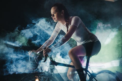 在人工烟雾中聚焦女运动员骑自行车 · 免费素材图片