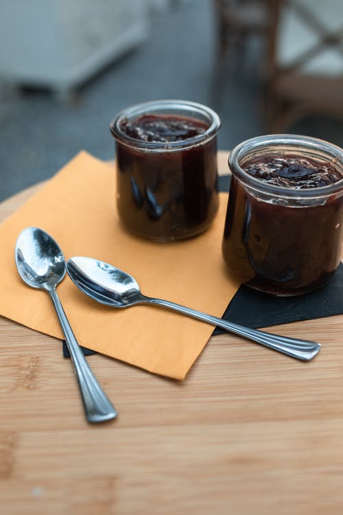棕色玻璃罐旁边的不锈钢勺子 · 免费素材图片