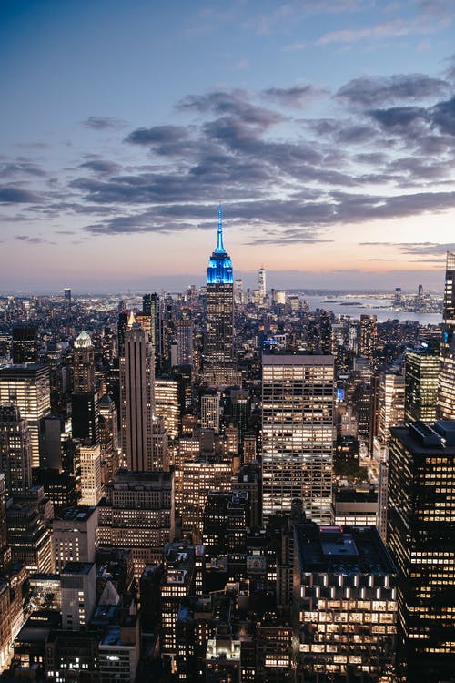 多云的夕阳的天空下曼哈顿的照明的摩天大楼 · 免费素材图片