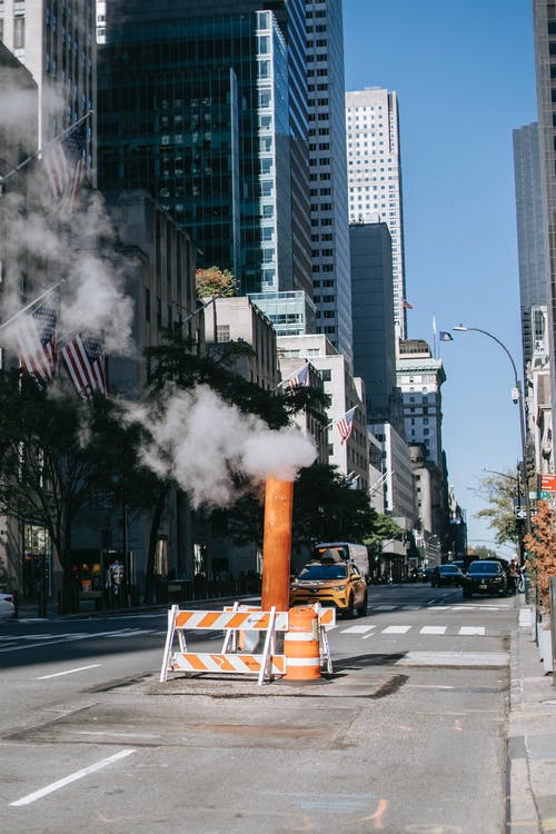 蒸气管在摩天大楼之间的道路上阳光灿烂的日子 · 免费素材图片