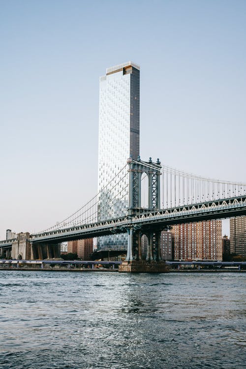 悬索桥和河后面的玻璃摩天大楼 · 免费素材图片