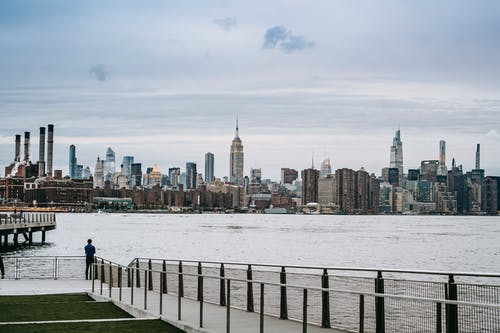 人站在大城市的河大堤上 · 免费素材图片