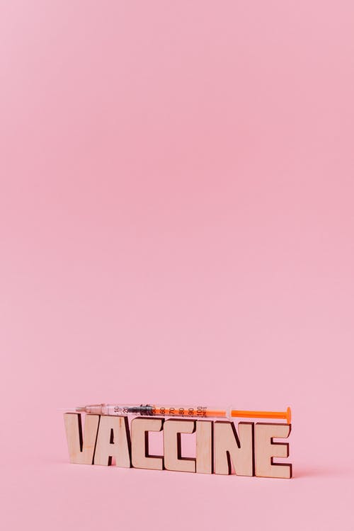 粉红色的背景上的注射器和疫苗刻字文本 · 免费素材图片