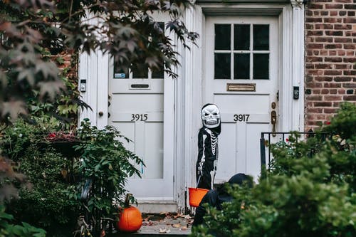 站在白色的木门附近的黑色和白色骨架服装的人 · 免费素材图片