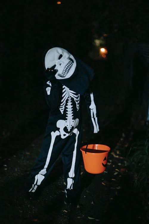 拿着橙色塑料桶的黑白骨骼服装的人 · 免费素材图片