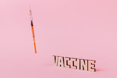 粉红色的背景上的注射器和疫苗文本 · 免费素材图片