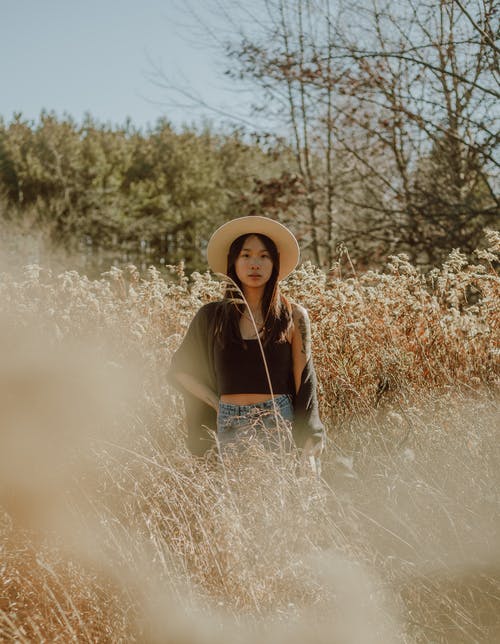 宁静的亚洲女人，站在郁郁葱葱的草地上 · 免费素材图片