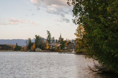 宁静的湖面，带有住宅别墅和秋天茂盛的树木，岸上 · 免费素材图片
