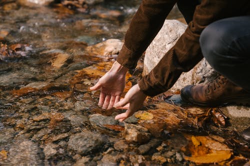 男人把手放在河里清澈的水 · 免费素材图片