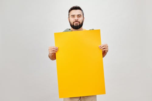 男子手持黄纸，白色背景 · 免费素材图片