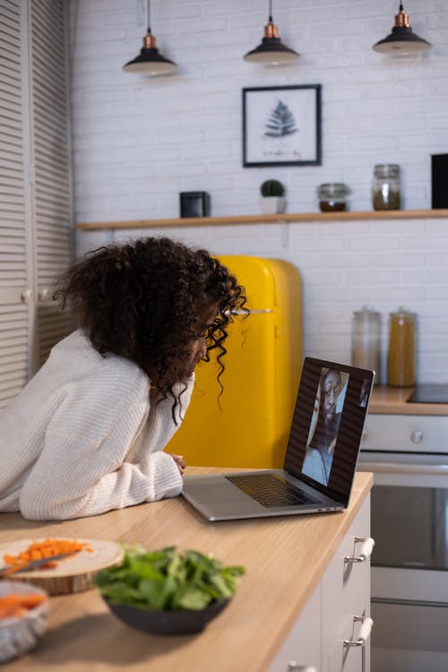 坐在黄色的椅子上，使用macbook Pro的白色毛衣的女人 · 免费素材图片