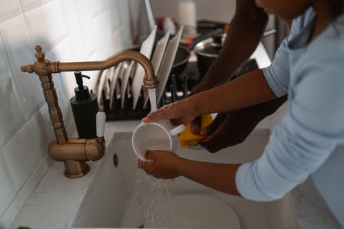 在厨房水槽上清洗杯子的人 · 免费素材图片