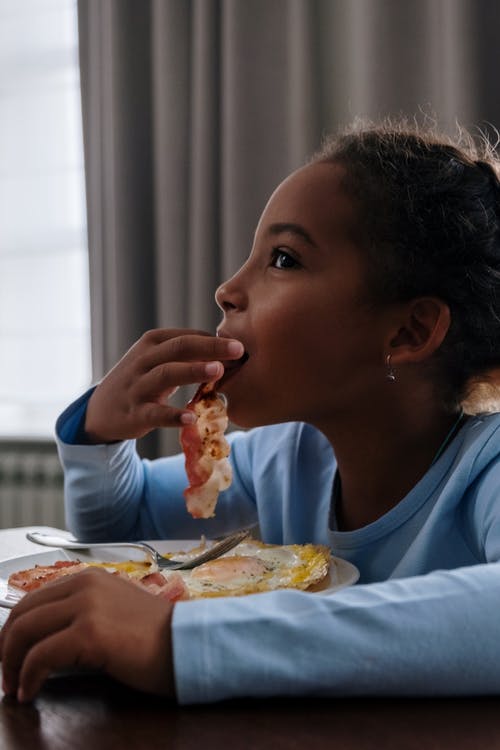 吃披萨的蓝色圆领t恤的女孩 · 免费素材图片